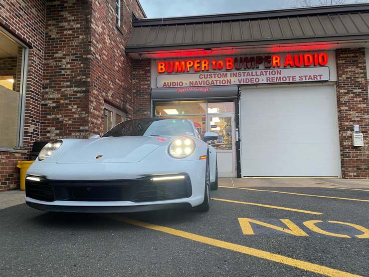 A white Porsche in front of Bumper to Bumper Car Audio